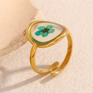 Macro detail of triangle acrylic ring with blue dried flower in 18K gold plated band