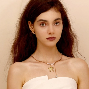 Model wearing gold starfish necklace and earrings set with elegant pearl accents