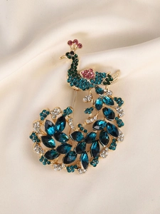 Close-up of elegant peacock brooch with colorful crystals on beige silk fabric