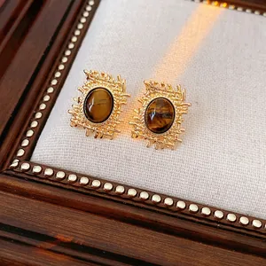 Retro tiger eye earrings with oval stones in hollow gold mesh baskets on linen