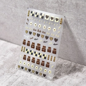 Macro detail of 5D embossed nail stickers featuring cute brown bears and gold accents