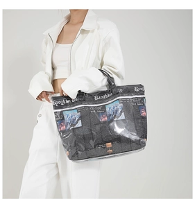 Detail view of the large newspaper print tote bag with glossy finish and reinforced handles