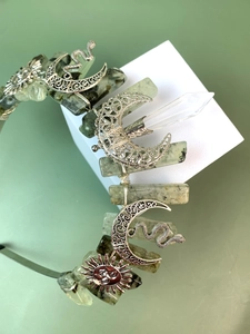 Close-up of silver crown headband with natural green crystals, moon and snake charms