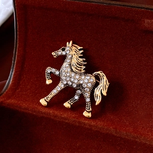 Macro shot of gold horse brooch with white rhinestones in a brown velvet gift box