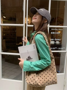 Borsa tote in tela a pois mostrata in un ambiente casual all'aperto con una modella reale