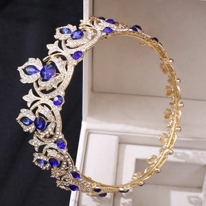 Close-up of a golden bridal crown featuring blue gemstones and crystal floral details