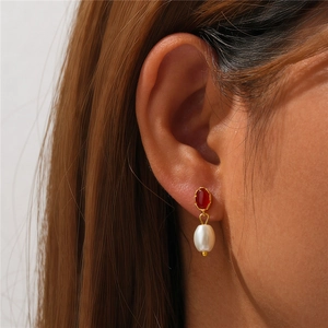 Detailed view of vintage gold earrings with red marquise stone and drop pearl on model