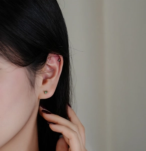 Detailed close-up of a s925 silver clover stud earring with green and black zircon stones