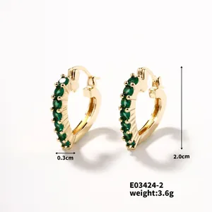 Detail view of gold heart-shaped hoop earrings with green zircon pavé settings