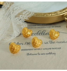 Detailed close-up of vintage gold woven heart earrings on an elegant romantic background