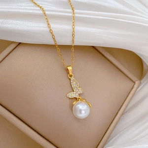 Detail view of gold butterfly necklace with sparkling crystals and a round pearl