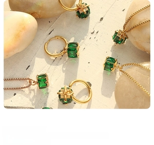 Detail view of gold necklace and earrings set with emerald green square cubic zirconia