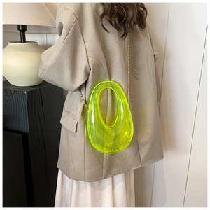 Detail of neon yellow transparent acrylic evening bag with metal chain strap