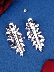 Detail of silver leaf hair clips with clear crystals and rhinestones set on blue fabric