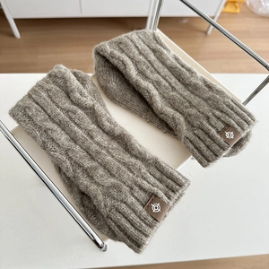 Greyish brown cable knit wool socks featuring a leather logo patch on a white rack