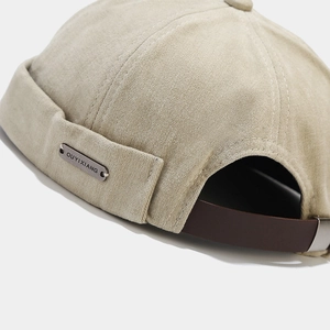 Bonnet docker en toile beige avec logo métallique et sangle de réglage en cuir marron