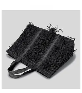 Close-up of the dense black tassel texture and woven fiber pattern on the tote bag