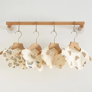 Macro detail of four assorted cotton gauze baby bibs with floral and animal prints