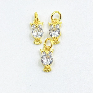 Detailed view of three golden owl pendants with round sparkling zircon stones on white