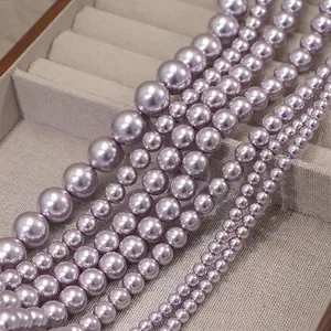 Macro shot of assorted lavender faux pearls in various sizes on a gray jewelry tray