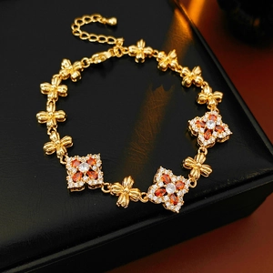 Detalle de una pulsera vintage de oro con circonitas rojas y blancas en cuero negro