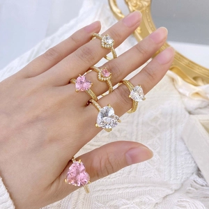 Close-up of gold rings featuring heart-shaped pink and clear cubic zirconia on hands
