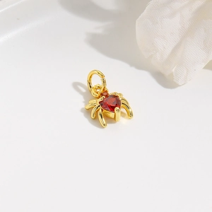 Macro detail of a gold spider charm featuring a red heart-shaped zircon gemstone