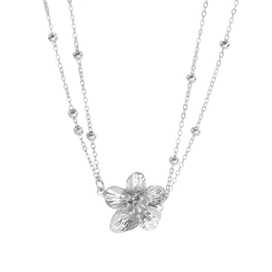 Macro-opname van een zilveren dubbellaagse ketting met een getextureerde bloemhanger