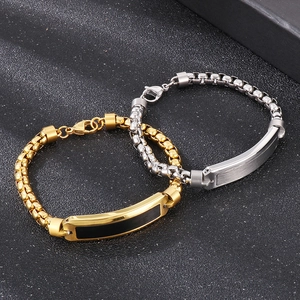 Detail view of gold and silver stainless steel ID bracelets on textured background