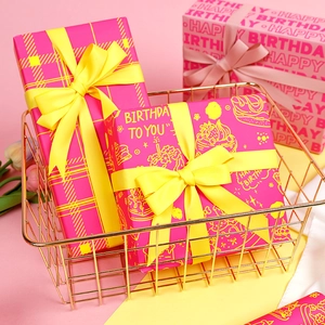 Pink and yellow birthday gift wrapping paper roll with satin ribbons in gold wire basket