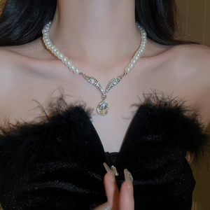 Detailed view of luxury teardrop crystal and white pearl necklace worn by a model