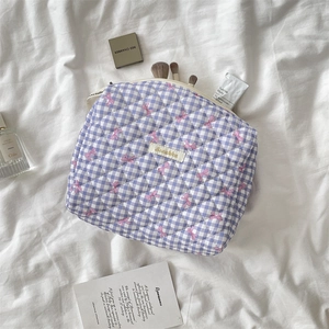 Detailed macro view of quilted lilac checkered makeup bag with pink bow pattern