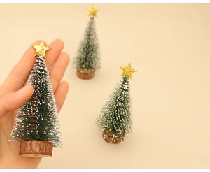 Miniature green Christmas pine trees with snow decor and wooden base set in hand