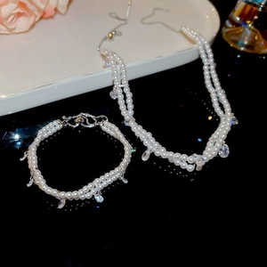 Detailed view of double-layer pearl necklace and bracelet set with teardrop zircon pendants