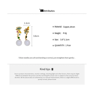 Détail de boucles d'oreilles asymétriques fleurs et scarabées avec zircons et perles