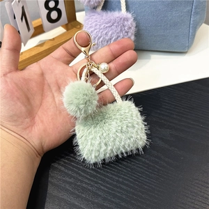 Mini plush bag keychain in mint green with pearl charm and golden clasp held in hand