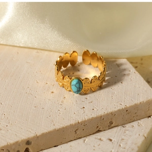 Close-up of 18K gold stainless steel leaf ring with an oval turquoise stone