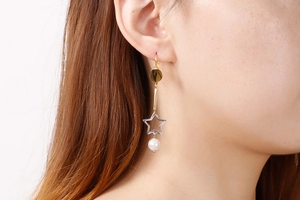 Vue rapprochée de longues boucles d'oreilles étoile en acier et perle portée