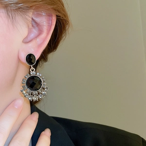 Close-up of vintage black gold drop earrings with crystals worn by a female model