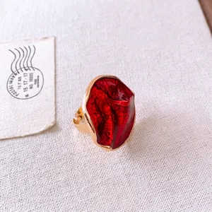 Vintage gold ring with oversized red textured stone on beige linen background