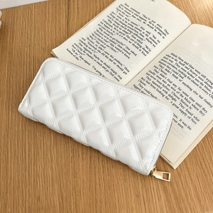 Close-up of white diamond-quilted patent leather wallet with elegant gold zipper detail