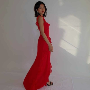Detail of red sleeveless long dress featuring ruffled edges and elegant side slit back view