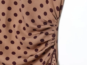 Detail of khaki midi dress featuring red polka dots and fine pleated ruching textures