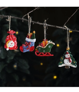 Close-up of resin Christmas ornaments with snowman and gift bag on dark branches