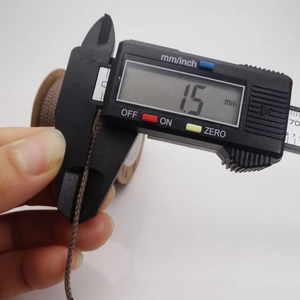 Macro shot of 1.5mm brown cotton cord being measured with a digital caliper