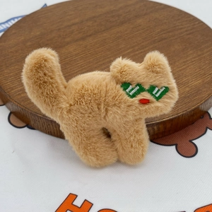 Detailed close-up of a plush cat brooch with green sunglasses on a wooden tray