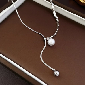 Detailed macro view of silver snake chain necklace featuring a white pearl pendant