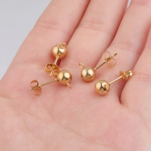 Golden round bead earrings with hanging loops for DIY jewelry making on a hand