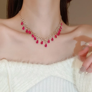 Macro shot of gold necklace with red teardrop gemstone and sparkling cubic zirconia