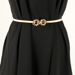 Detail of gold elastic metal waist chain with infinity symbol buckle on black dress